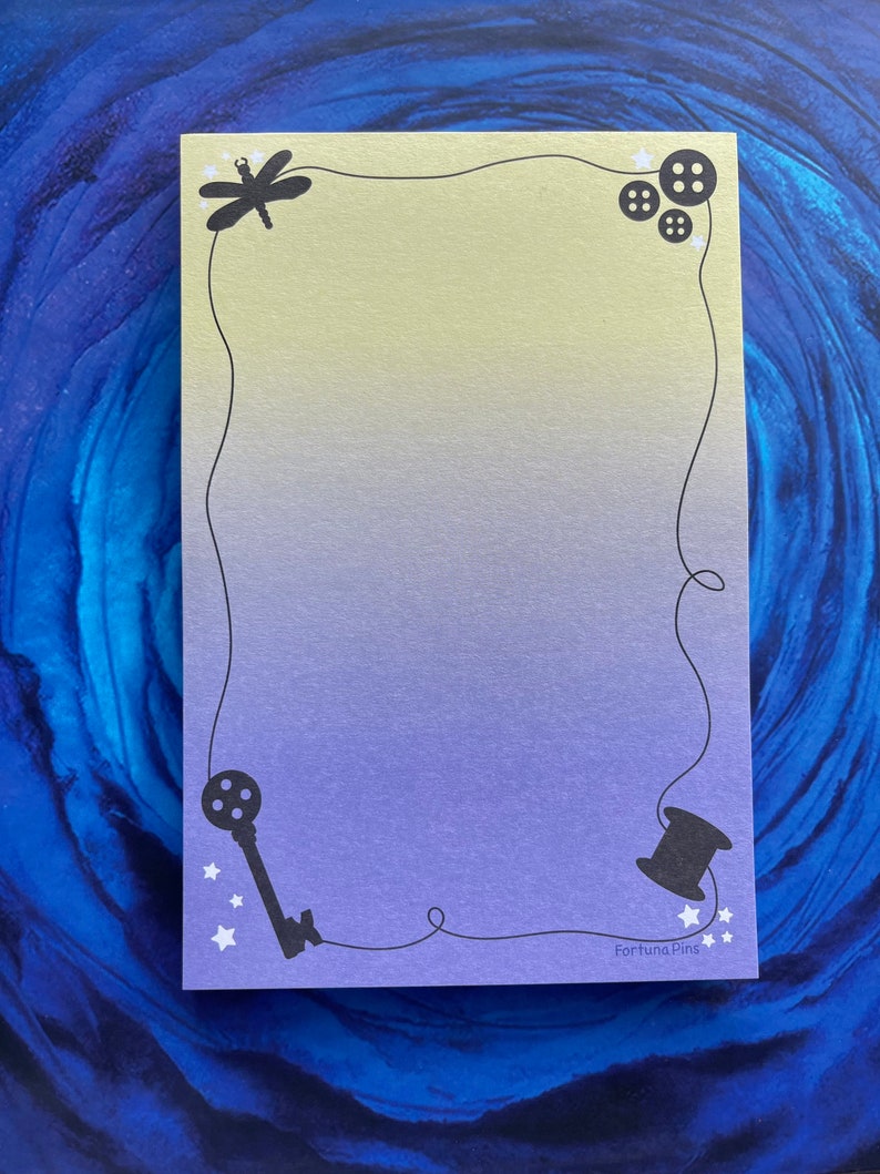 May include: A yellow and purple gradient card with a black border. The border is decorated with a dragonfly, buttons, a key, and a spool of thread. The card has the text "Fortuna Pins" in the bottom right corner.