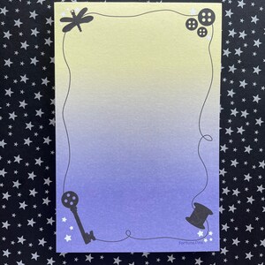 May include: A light blue and yellow gradient card with a dragonfly, buttons, a key, and a spool of thread in the corners. The card has a white border and the text "Fortuna Pins" in the bottom right corner.