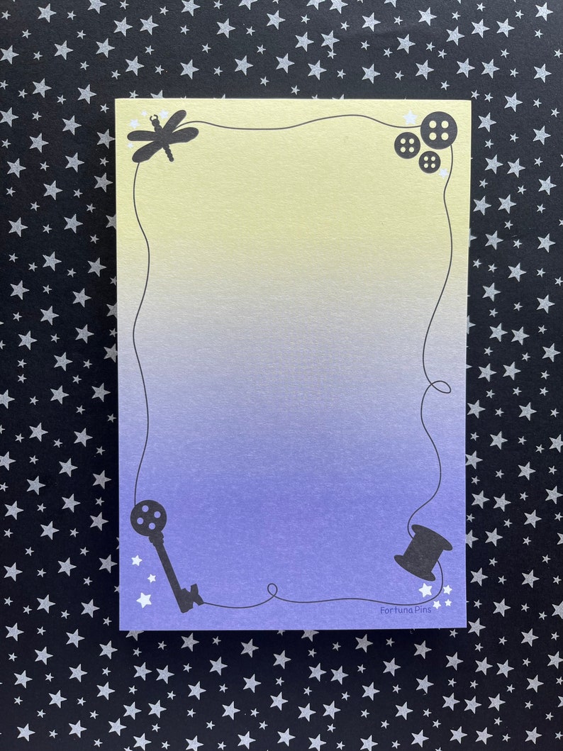 May include: A light blue and yellow gradient card with a dragonfly, buttons, a key, and a spool of thread in the corners. The card has a white border and the text "Fortuna Pins" in the bottom right corner.