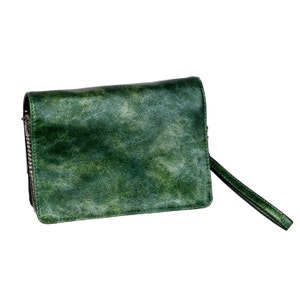 Può includere: Una pochette in pelle verde con chiusura a zip e una lunga tracolla.