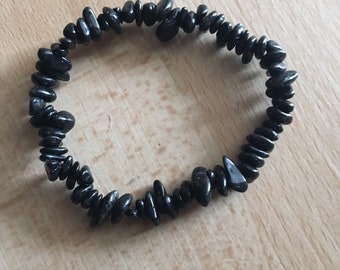 May include: A black gemstone bracelet made of small, irregularly shaped stones.