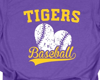 May include: Purple t-shirt with the word "TIGERS" in yellow block letters above two baseballs and the word "Baseball" in yellow script. The shirt is made of a soft material and is suitable for casual wear.