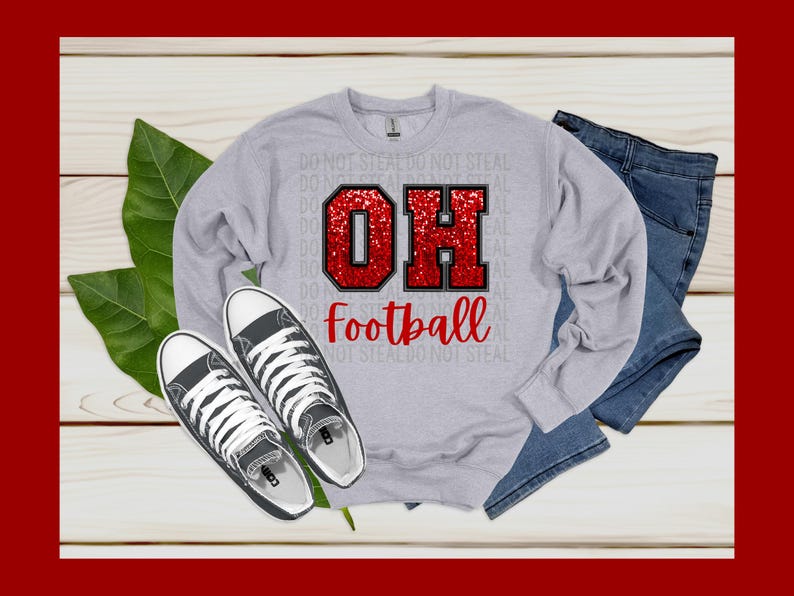 Może przedstawiać: Szara bluza z nadrukiem czerwonego brokatu &bdquo;OH&rdquo; i napisem &bdquo;football&rdquo; z przodu. Bluza leży na drewnianej powierzchni z parą czarnych but&oacute;w z pł&oacute;tna i parą niebieskich dżinsowych szort&oacute;w.