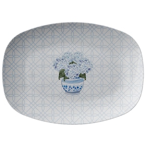May include: A white oval serving platter with a blue and white geometric pattern. A blue and white vase with blue hydrangeas is in the center of the platter.