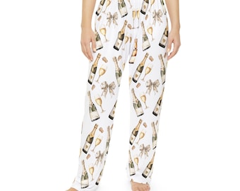 May include: White pajama pants with a champagne bottle and glass print. The print is in shades of gold and brown.