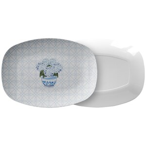 May include: A white oval serving platter with a blue and white floral pattern. The pattern features a bouquet of blue hydrangeas in a blue and white vase. The platter has a delicate lattice design.