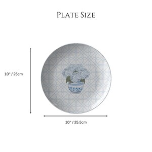 May include: A 10-inch white ceramic plate with a blue and white floral design. The plate features a repeating pattern of blue circles and a floral motif in the center. The floral motif is a bouquet of blue hydrangeas in a blue and white vase.