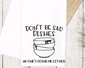 May include: White kitchen towel with black text that reads "Don't be sad dishes, no one's doing me either."  A stack of three bowls with dripping liquid is illustrated below the text.