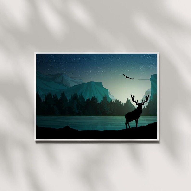 May include: A framed landscape art print featuring a silhouette of a deer with large antlers standing near a lake. The background shows mountains, a forest, and a starry night sky. An eagle flies overhead.