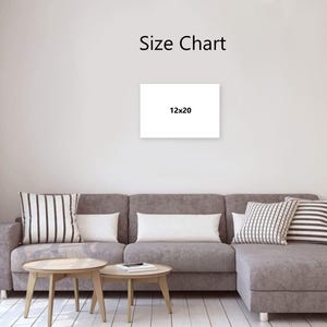 May include: A white canvas with the text "Size Chart" and "12x20" displayed on a wall. The canvas is above a gray sectional sofa with decorative pillows and two wooden coffee tables.