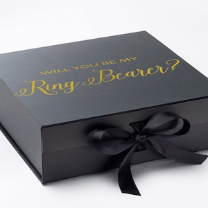 May include: Black gift box with a black ribbon and the text "Will you be my Ring Bearer?" in gold lettering.