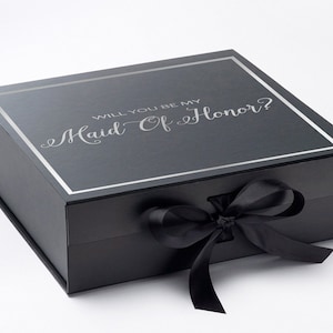 May include: Black gift box with a silver ribbon and the text "Will you be my Maid of Honour?" printed on the lid.