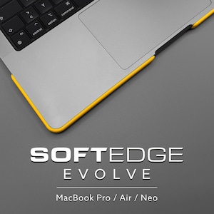 Pode incluir: Um portátil prateado com teclado e trackpad pretos, apresentando uma borda protetora amarela brilhante ao longo das extremidades. O texto SOFTEDGE EVOLVE MacBook Pro / Air / Neo é exibido em letras brancas sobre um fundo cinzento.