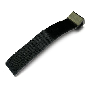 May include: A black hook and loop strap, also known as a Velcro strap, against a white background. The strap is made of a textured, woven material and features a hook and loop closure. The strap is used for securing items.