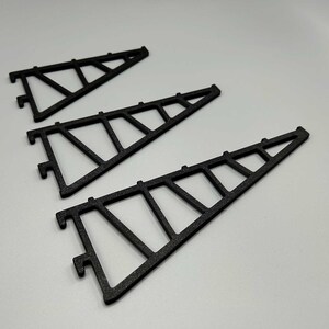 May include: Three black metal shelf brackets in a triangular design. Each bracket features a series of interconnected geometric shapes, creating a sturdy support structure. The brackets are designed to be mounted on a wall to hold shelves.