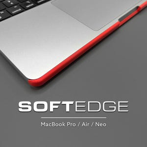 Peut inclure: Un ordinateur portable argenté avec une bordure de protection rouge vif installée sur le côté. Le texte SOFTEDGE est imprimé sous l'ordinateur, suivi du texte MacBook Pro / Air / Neo. L'ordinateur possède un clavier noir et un pavé tactile argenté.