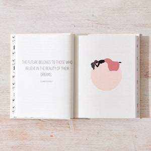 May include: An open journal with a white background and black lines. The left page has a quote that reads "The future belongs to those who believe in the beauty of their dreams." The right page has a simple illustration of a person lying on a pink circle.