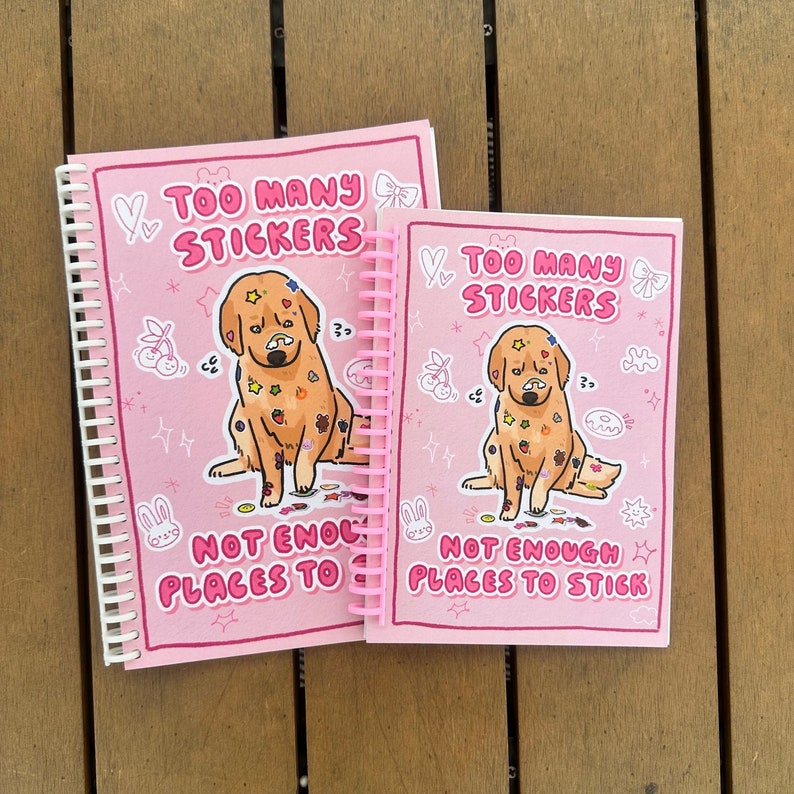 Pink sticker book with cover illustration of a cute golden retreiver dog on a pink background. The dog has lots of stickers stuck on its fur. Text says "Too many sticker, not enough places to stick"