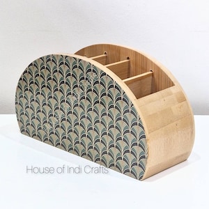 Könnte beinhalten: Ein hölzerner Schreibtisch-Organizer mit halbkreisförmigem Design. Die Vorderseite zeigt ein sich wiederholendes Fächermuster in Grün-, Schwarz- und Beigetönen. Der Organizer hat mehrere Fächer zur Aufbewahrung und der Text "House of Indi Crafts" ist sichtbar.