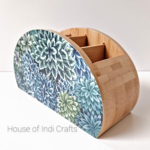 Peut inclure: Un organisateur en bambou demi-rond avec un motif floral bleu et vert. L'organisateur a trois compartiments et est parfait pour ranger des stylos, des crayons ou d'autres petits objets.