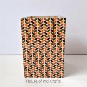 Könnte beinhalten: Ein rechteckiger Holzbehälter mit einem sich wiederholenden Blattmuster in Braun-, Orange- und Grüntönen auf beigem Hintergrund. Der Text "House of Indi Crafts" ist unten aufgedruckt.
