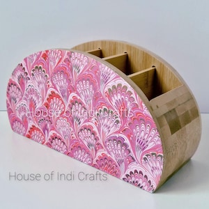 Könnte beinhalten: Ein Schreibtisch-Organizer aus Holz mit halbkreisförmigem Design. Die Vorderseite zeigt ein rosa, rotes und weißes Marmormuster. Der Organizer hat vier Fächer und der Text "House of Indi Crafts" ist sichtbar.