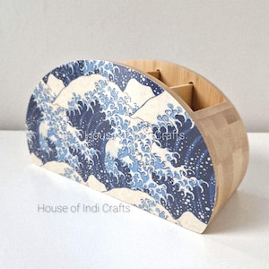 Könnte beinhalten: Ein Schreibtisch-Organizer aus Holz mit halbkreisförmigem Design. Die Vorderseite zeigt ein blau-weißes Wellenmuster mit dem Text "House of Indi Crafts" unten. Der Organizer hat mehrere Fächer für Stifte und andere Büromaterialien.