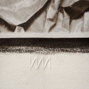May include: A close-up of a white, textured surface with the letters "WM" embossed in the center.