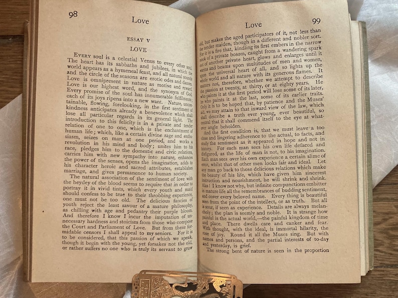 May include: Open book with text on aged paper, featuring the word "Love" at the top of the page. The book is open to two pages with text, and a decorative metal clasp is visible at the bottom.