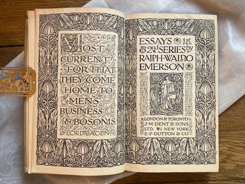 May include: Open book with decorative black and white illustrations and text. The left page reads "MOST CURRENT FOR THAT THEY COME HOME TO MENS BUSINESS & BOSOMS LORD BACON." The right page reads "ESSAYS 1st & 2nd SERIES by RALPH WALDO EMERSON."