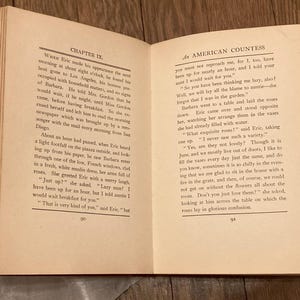Puede incluir: Un libro abierto con p&aacute;ginas amarillentas y envejecidas. La p&aacute;gina izquierda muestra "CHAPTER IX." y la p&aacute;gina derecha dice "AN AMERICAN COUNTESS." El texto llena las p&aacute;ginas, con un lomo rojo visible.