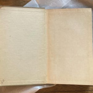 May include: An open vintage book with aged, cream-colored pages. The book's spine is visible, and the pages are slightly yellowed with age. The number "60" is handwritten in the lower left corner. The book is resting on a wooden surface.