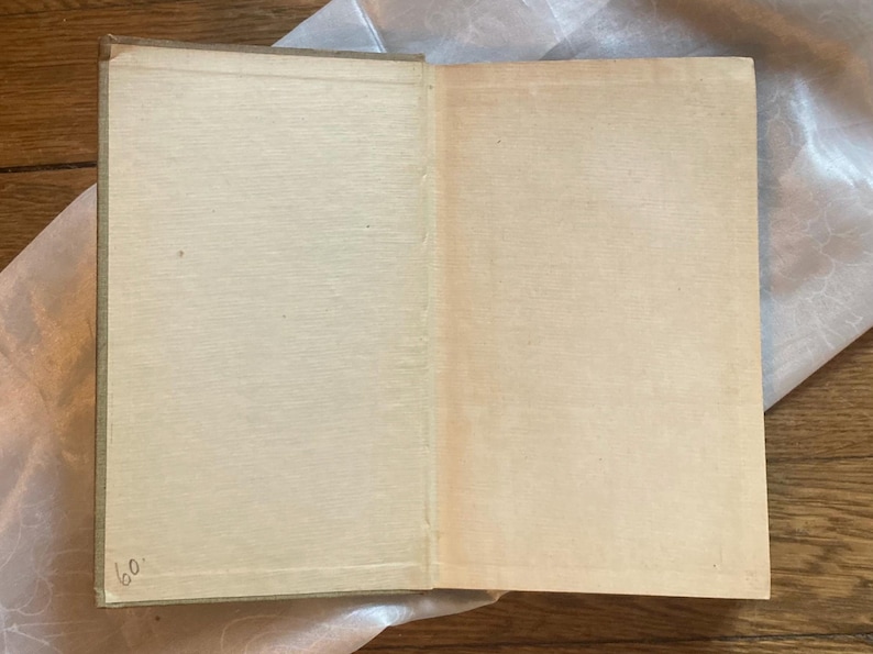May include: An open vintage book with aged, cream-colored pages. The book's spine is visible, and the pages are slightly yellowed with age. The number "60" is handwritten in the lower left corner. The book is resting on a wooden surface.
