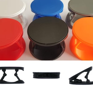 May include: Six different coloured phone grips with a black base. The grips are round and have a smooth surface. The colours are white, blue, grey, red, black, and orange.