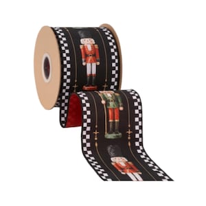 May include: A spool of black ribbon featuring a repeating pattern of nutcracker figures in red and green uniforms. The edges of the ribbon are decorated with a black and white checkered border, and small gold fleur-de-lis accents are placed between each nutcracker.