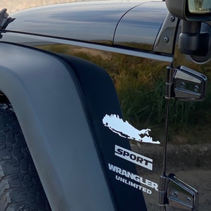 Puede incluir: Jeep Wrangler Unlimited Sport negro con una calcomanía blanca de Long Island en el lateral.