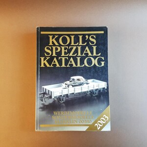 Op de afbeelding: Een zwart en gouden boek getiteld "Koll's Spezial Katalog" met een afbeelding van een modeltreinwagen en een auto op de omslag. Het boek is uit 2003.