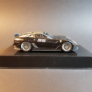 May include: A black and silver model car with the number "55" on the side. The car is on a black display stand.