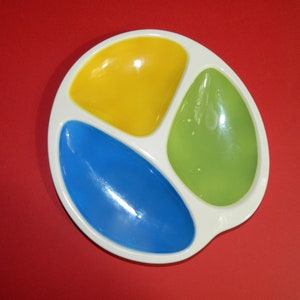 May include: A white ceramic divided dish with three sections. The sections are coloured yellow, blue, and green.