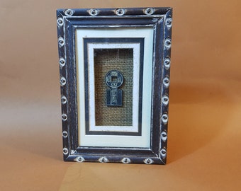 Cadre sous verre d'une reproduction monnaie ancienne Asiatique sur fond en toile de jute avec crochet de suspenssion 22,5x15,5x3Cm