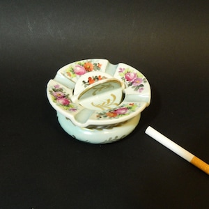 Cendrier boule en porcelaine centre tournant et amovible aux decors fleuris et or signé diametre 11Cm hauteur 7Cm 300Gr qqs traces du temps