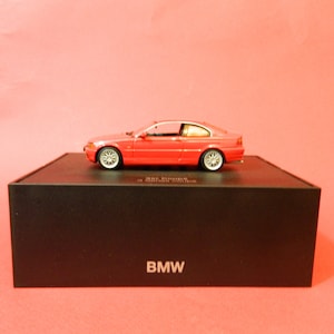 May include: A red BMW 3 Series Coupe model car in a black box with the word "BMW" printed on the front.