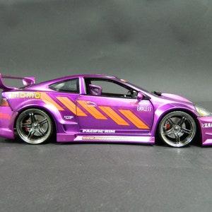 May include: Purple and orange model car with a large rear wing, "Momo" and "Endless" decals, and "Pacific Rim" printed on the side.