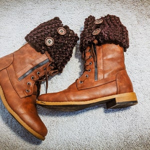 May include: Brown leather boots with brown knitted cuffs and buttons. The boots have laces and zippers.