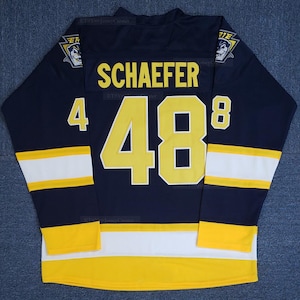 May include: A navy blue hockey jersey featuring the name "SCHAEFER" and the number "48" in yellow. The jersey has yellow and white stripes on the sleeves and hem, and a team logo on the shoulders.