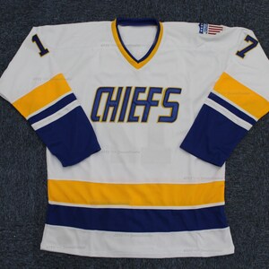 May include: White hockey jersey with blue and gold stripes. The jersey has the word "CHIEFS" in blue on the front and the numbers "1" and "7" on the sleeves.