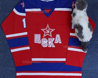 May include: Red and blue hockey jersey with white stripes and the word "ЦСКА" in white letters. The jersey has a red star with a hammer and sickle in the center.