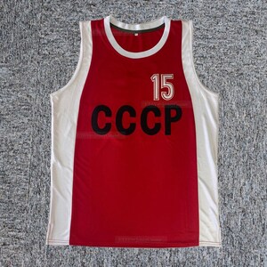 Puede incluir: Jersey rojo y blanco sin mangas con el texto "CCCP" y el número "15" en negro.
