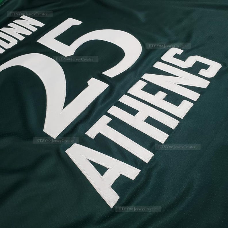 Puede incluir: Primer plano de una camiseta verde oscuro con letras y n&uacute;meros blancos. El n&uacute;mero "25" se muestra de forma destacada, con el nombre "DUNN" encima. Tambi&eacute;n se ve la palabra "ATHENS". La camiseta tiene una textura de malla.