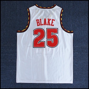 May include: White basketball jersey with black and yellow trim. The back of the jersey has the name "BLAKE" and the number "25" in red.